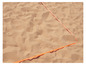 Une ligne orange sur le sable, probablement pour un terrain de volley-ball.