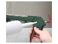 Une main tient un pistolet à calfeutrer vert et rouge avec un tube de mastic blanc inséré.