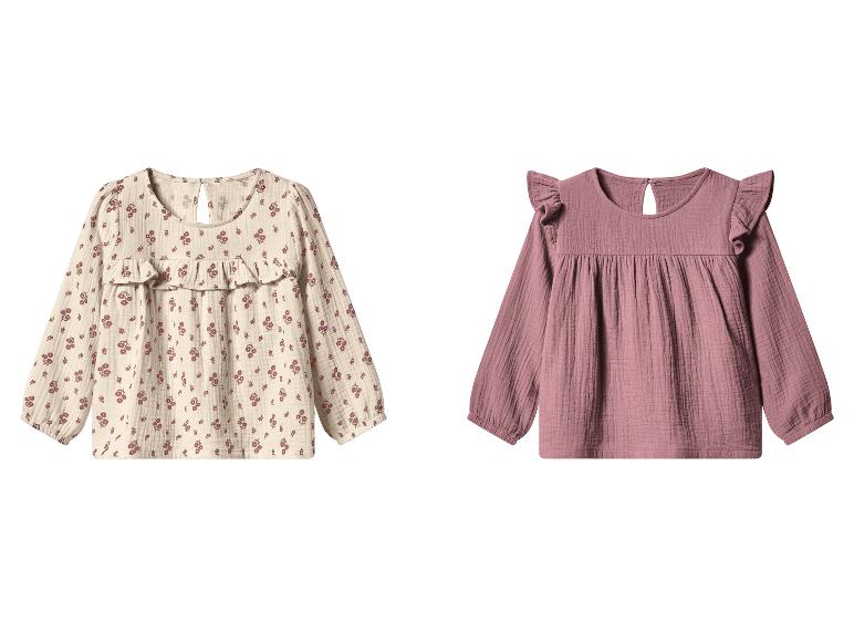 Deux chemisiers pour enfants, un beige à imprimé floral et un rose uni, tous deux à manches longues.