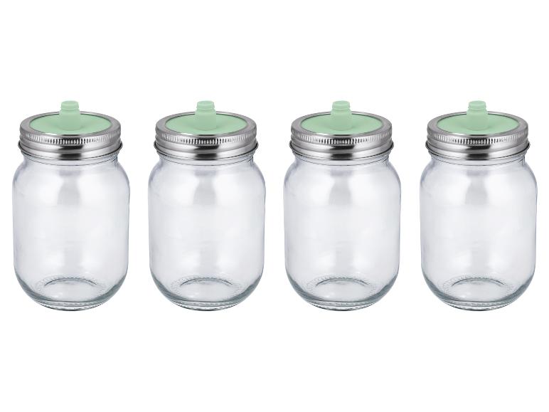 Quatre bocaux en verre avec couvercles métalliques et valves de fermentation vertes