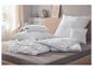 Oreillers et couettes blancs sur un lit, avec des étiquettes bleues Hydrocool.