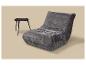 Fauteuil lounge gris rembourré avec une petite table d'appoint noire sur fond clair.