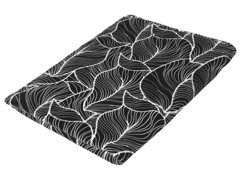 Plaid polaire noir à motif de feuilles blanches, plié.