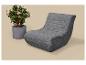Fauteuil de relaxation gris avec plante en pot à fleurs roses sur fond beige.