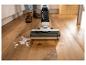 Aspirateur balai sans fil pour liquides et solides nettoyant un déversement sur un parquet.