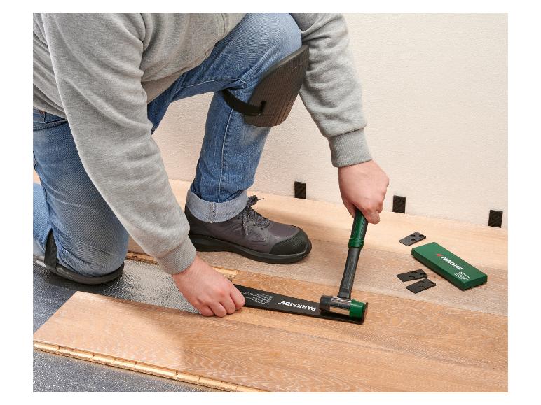 Homme posant du parquet stratifié avec un maillet en caoutchouc et des cales.