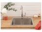 Évier de cuisine avec robinet, plan de travail en bois, mur de briques blanches, branches d'eucalyptus.