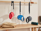 Trois laisses Flexi en rouge, bleu et noir, suspendues à une barre en bois.