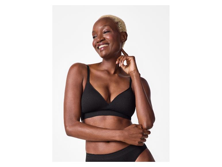 Femme souriante aux cheveux blonds courts, portant un soutien-gorge et une culotte noirs.
