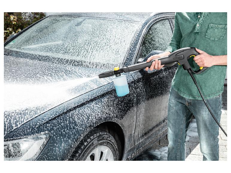 Homme lavant une voiture avec un nettoyeur haute pression et une buse à mousse.