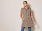 Une femme porte un long gilet en duvet marron
