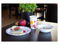 Une tasse, une assiette et un bol à thème Mickey Mouse avec un sandwich, des fruits et des céréales pour le petit-déjeuner.