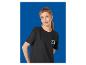 Femme en t-shirt noir avec un logo coloré, posant devant un fond bleu.