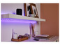Un haut-parleur sans fil noir sur une étagère blanche avec un éclairage LED violet.