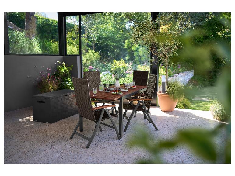 Ensemble de salle à manger extérieur avec table et chaises marron, sur une terrasse avec jardin verdoyant.