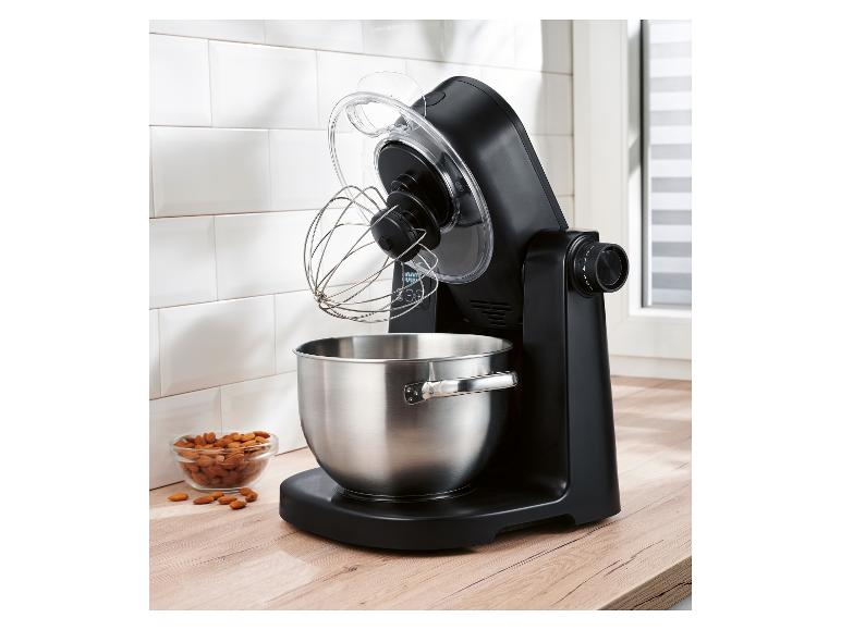 Robot pâtissier noir avec bol en acier inoxydable et fouet sur un comptoir en bois.