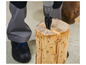 Une personne utilise une perceuse pour fixer un fendeur de bois dans un tronc d'arbre.