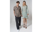 Un homme et une femme posent en tenue décontractée, il porte une chemise à imprimé et elle une robe verte.