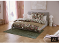 Chambre avec lit double, parure de lit fleurie et rayée, et tapis vert.