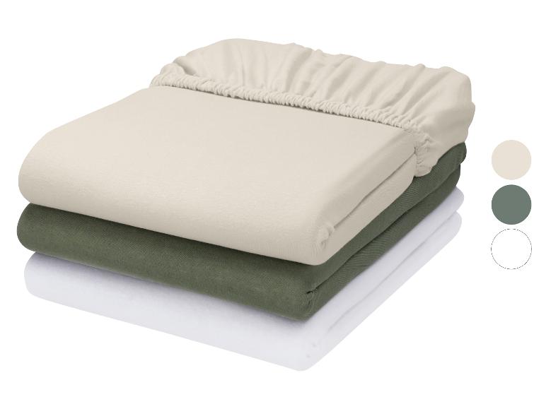 Pile de trois draps-housses en beige, vert et blanc avec des échantillons de couleur.