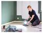 Femme ajustant la lampe de travail LIVARNO® «The Painter+» dans une pièce aux murs peints.