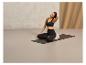 Une femme assise sur un tapis de yoga avec un coussin pour soutien.
