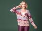 Une femme porte un pull de Noël rose avec un col en V et un pantalon rouge.
