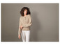 Une femme porte un pull beige et un pantalon blanc.