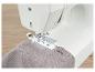 Machine à coudre réalisant une boutonnière sur du tissu.