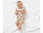 Bébé souriant vêtu d'un ensemble rayé sur un plaid blanc.