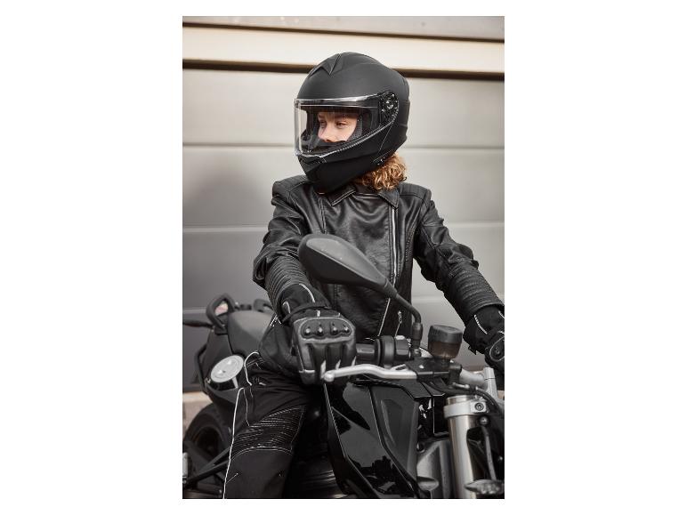 Femme en casque de moto noir, veste en cuir et gants sur une moto
