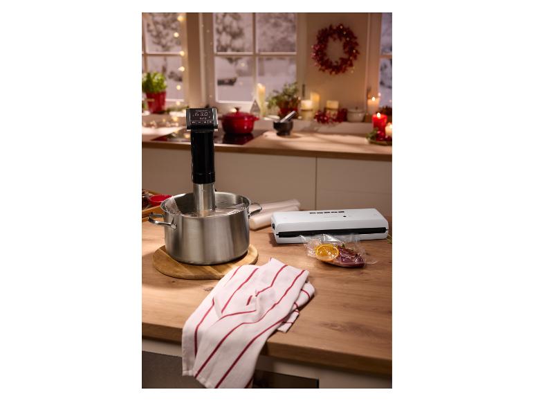 Appareil sous vide dans une casserole, scelleuse sous vide et aliments scellés sous vide sur un comptoir de cuisine.