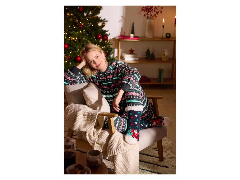 Femme en pyjama de Noël assise dans un fauteuil à côté d'un sapin de Noël.