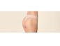 Dos d'une femme en string rose clair sur fond beige.