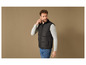Un homme portant un gilet matelassé noir et un t-shirt à manches longues gris.