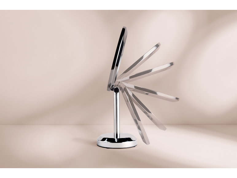 Miroir de maquillage chromé avec inclinaison réglable sur fond beige.