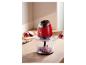 Un hachoir compact rouge sur une table en bois hache des oignons.