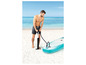 Un homme gonfle un paddleboard gonflable avec une pompe manuelle sur la plage.