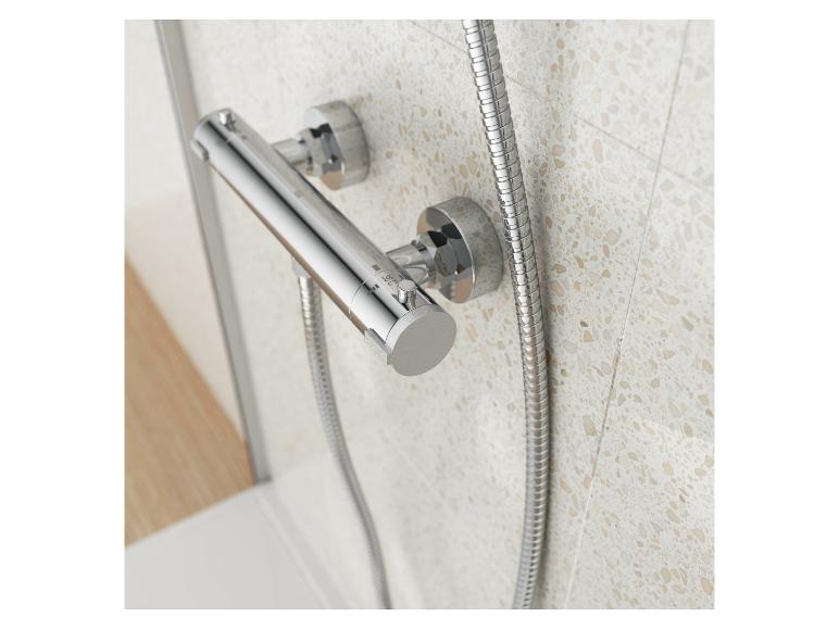 Un thermostat de douche chromé avec un tuyau flexible.