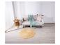 Un canapé beige avec une couverture menthe et un tapis rond en jute dans une pièce lumineuse.