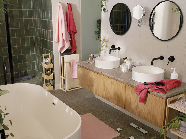 Une salle de bain avec une baignoire, un lavabo, un miroir, un tapis de bain, une balance et des serviettes.