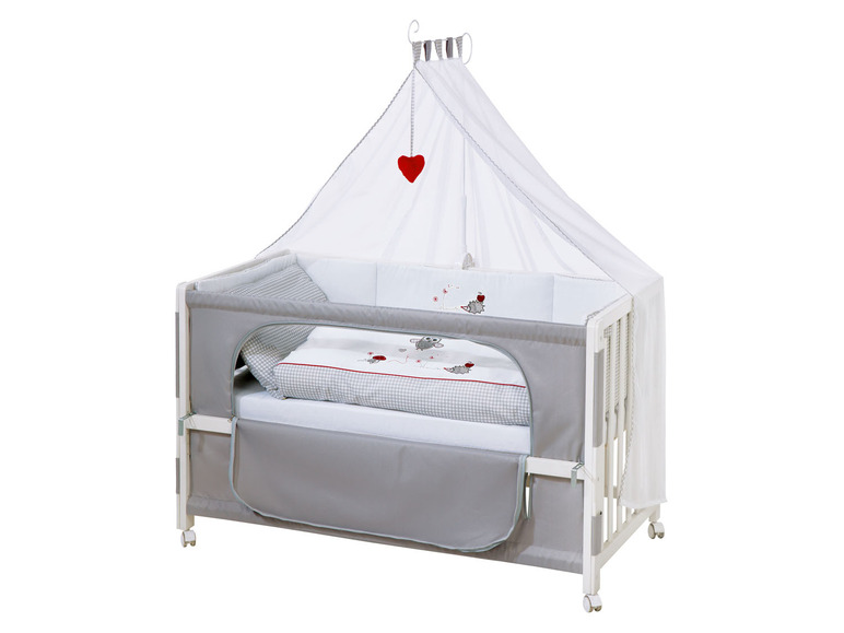 Lit bébé avec un ciel de lit blanc et des draps gris.