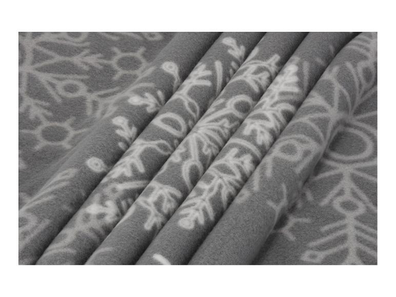 Couverture polaire grise avec motifs de flocons de neige blancs.