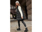 Une femme porte un gilet matelassé noir, un pantalon noir et des bottes noires.