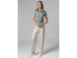 Une femme porte un t-shirt bleu clair à motif et un pantalon beige.