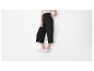 Femme portant un pantalon large noir et des baskets blanches.
