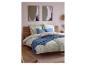 Chambre avec lit en bois, housse de couette florale, oreillers bleus et art mural abstrait.
