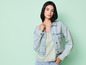 Une femme portant une veste en jean bleu clair et un chemisier à rayures.