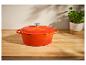 Cocotte orange en fonte sur une table en bois.