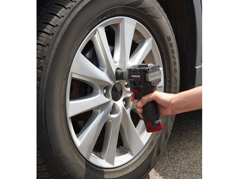 Personne utilisant une clé à chocs pour changer un pneu de voiture.